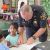A picture of a sheriff's deputy teaching children about finger printing
